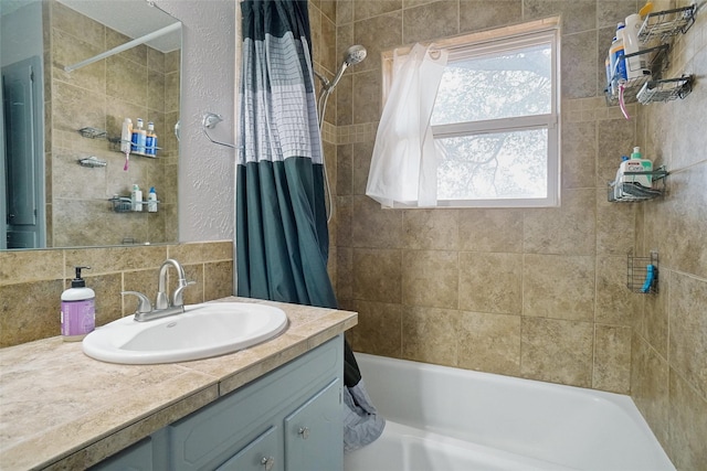 bathroom featuring vanity, tasteful backsplash, a textured wall, and shower / bath combo with shower curtain