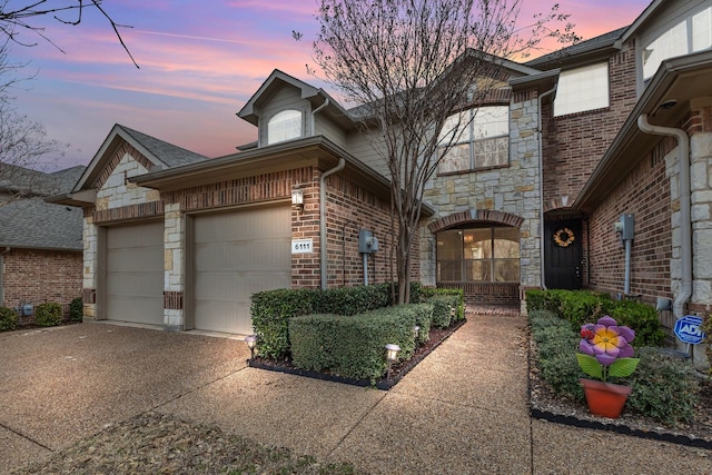 view of front of property featuring brick siding, stone siding, driveway, and an attached garage