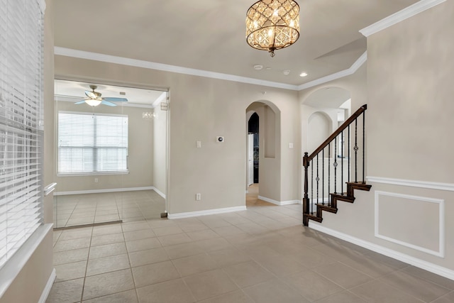 tiled empty room with stairway, baseboards, arched walkways, ornamental molding, and ceiling fan with notable chandelier