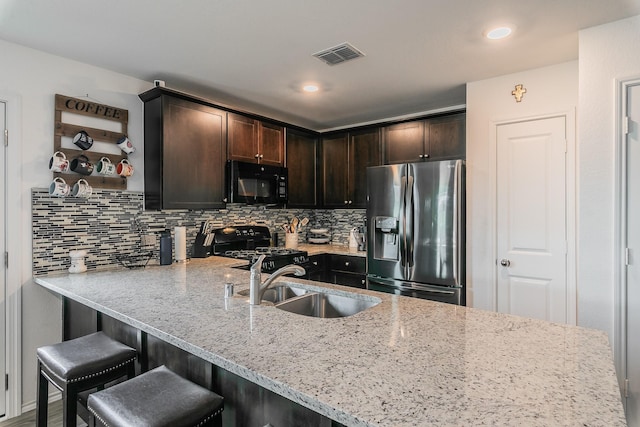 kitchen with visible vents, a sink, decorative backsplash, black appliances, and dark brown cabinets