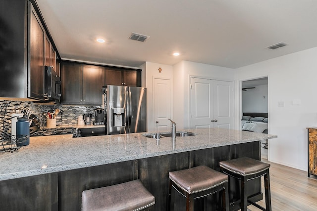 kitchen with visible vents, stainless steel fridge, black microwave, and a sink