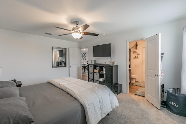 bedroom with visible vents, light carpet, ensuite bath, and a ceiling fan