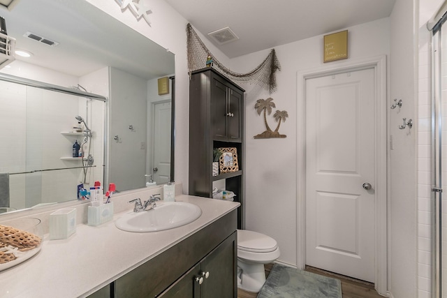 full bathroom with a tile shower, visible vents, toilet, and vanity