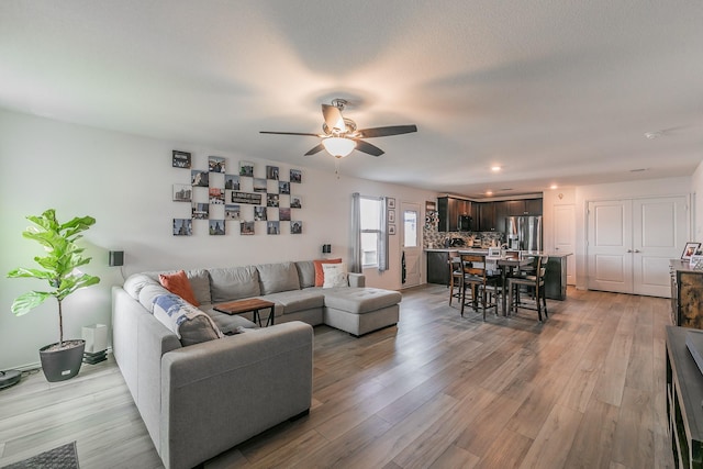 living area with light wood-style flooring, recessed lighting, and a ceiling fan