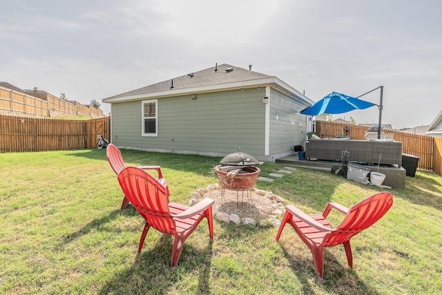 rear view of property with a lawn, a fire pit, and a fenced backyard