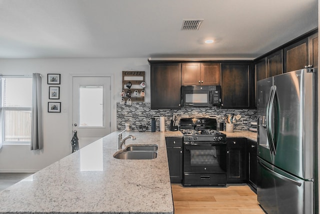 kitchen with visible vents, backsplash, a peninsula, black appliances, and a sink