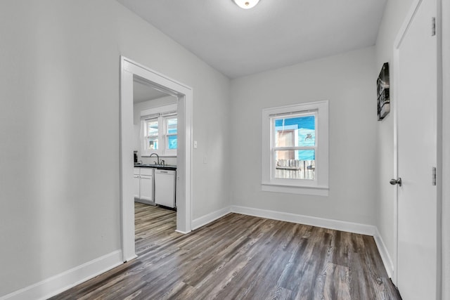 empty room featuring baseboards, dark wood-style flooring, and a sink