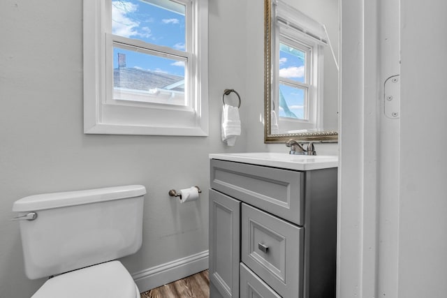 bathroom with vanity, toilet, wood finished floors, and baseboards