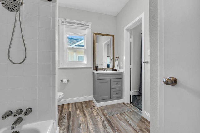 full bath featuring vanity, washtub / shower combination, wood finished floors, baseboards, and toilet