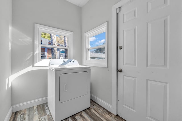 clothes washing area featuring baseboards, washer / dryer, wood finished floors, and laundry area