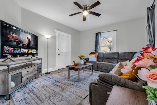 living area featuring a ceiling fan, baseboards, and wood finished floors