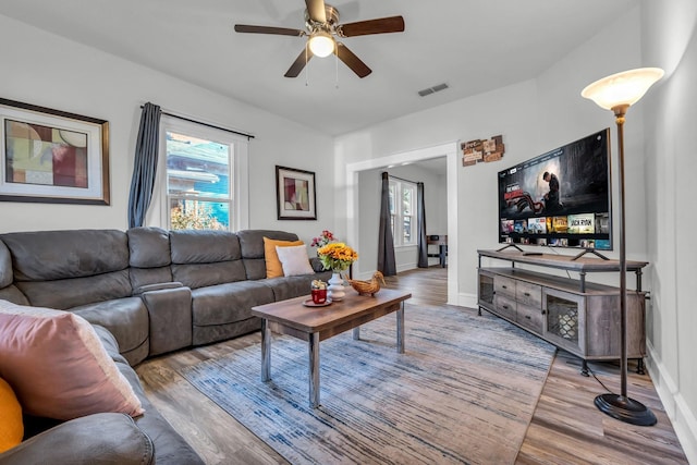 living area featuring visible vents, a ceiling fan, baseboards, and wood finished floors