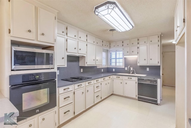 kitchen with black appliances, white cabinets, light floors, and a sink