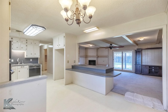 kitchen featuring black dishwasher, open floor plan, a peninsula, white cabinets, and a fireplace