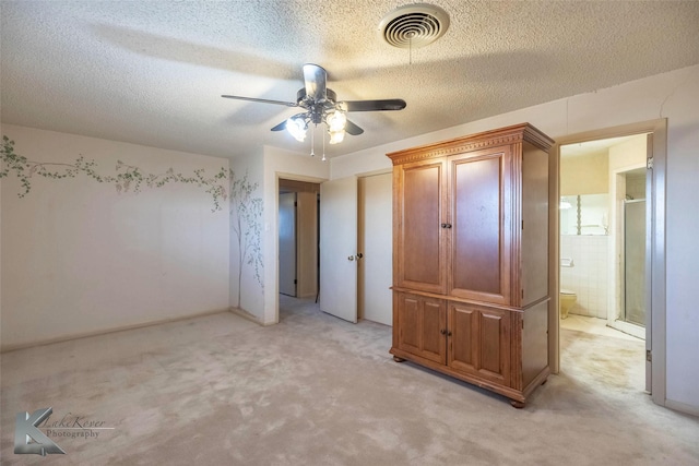 unfurnished bedroom with connected bathroom, light colored carpet, visible vents, and a textured ceiling