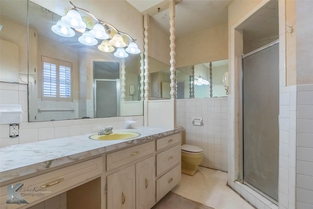 full bathroom with vanity, a wainscoted wall, a shower stall, tile walls, and toilet