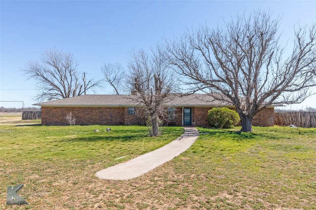 view of front facade with brick siding, a front lawn, and fence