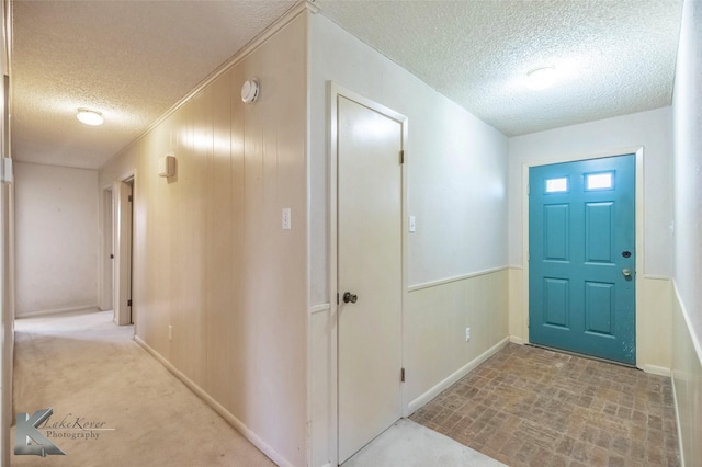 foyer entrance with wooden walls, wainscoting, and a textured ceiling