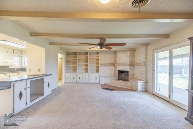 unfurnished living room featuring visible vents, beam ceiling, a fireplace, a textured ceiling, and light colored carpet