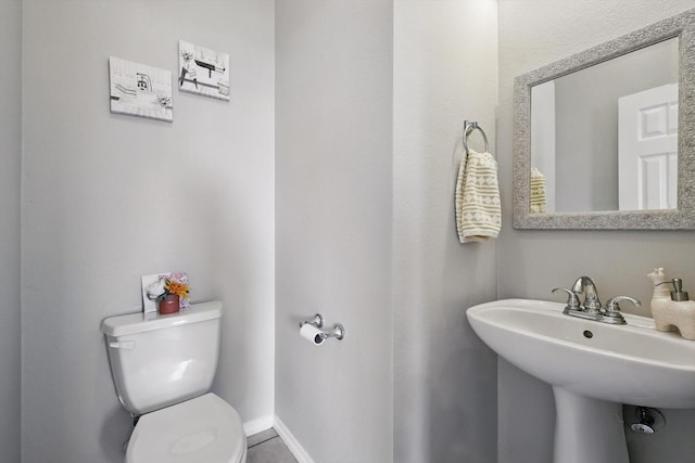 bathroom with toilet, baseboards, and a sink