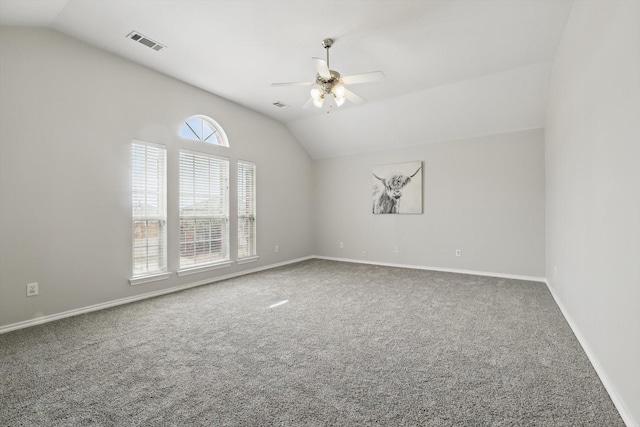 carpeted spare room with visible vents, lofted ceiling, baseboards, and ceiling fan