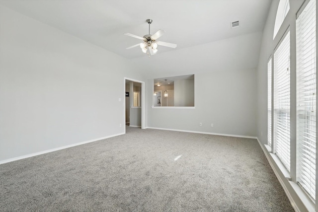 carpeted empty room with visible vents, baseboards, a ceiling fan, and vaulted ceiling