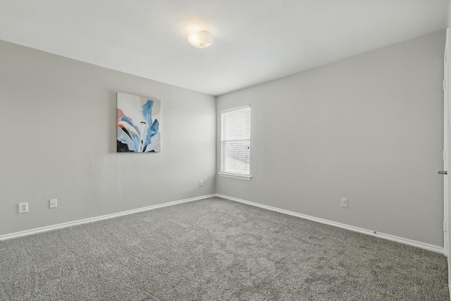 unfurnished room featuring carpet and baseboards