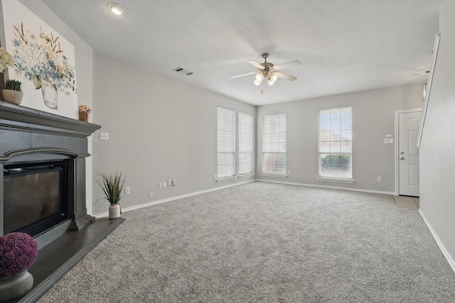 unfurnished living room featuring visible vents, a fireplace with flush hearth, carpet floors, and ceiling fan