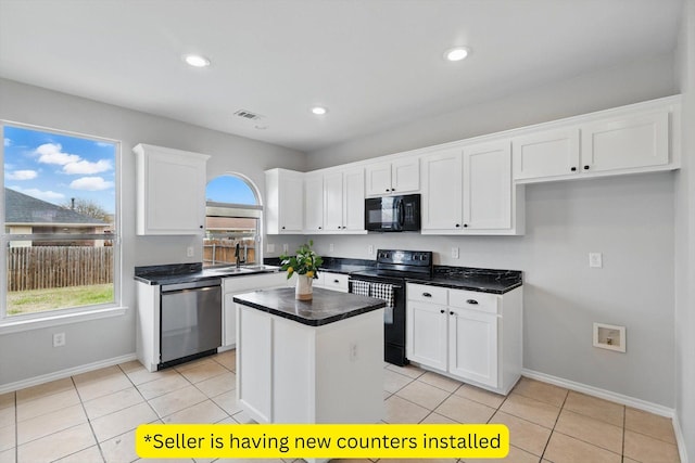 kitchen featuring visible vents, black appliances, dark countertops, a center island, and white cabinetry