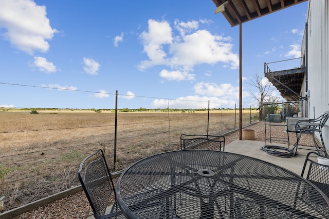 view of yard with outdoor dining space, a patio area, and a rural view