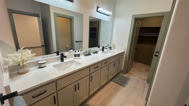 bathroom featuring double vanity, a spacious closet, and a sink