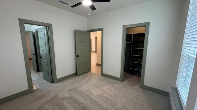 unfurnished bedroom featuring visible vents, light carpet, connected bathroom, baseboards, and a spacious closet