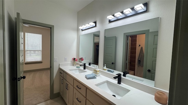 full bathroom featuring double vanity, baseboards, and a sink