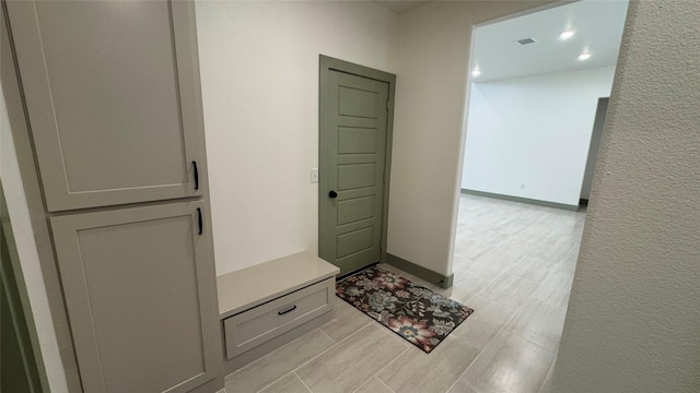 mudroom with visible vents, baseboards, wood tiled floor, and a textured wall