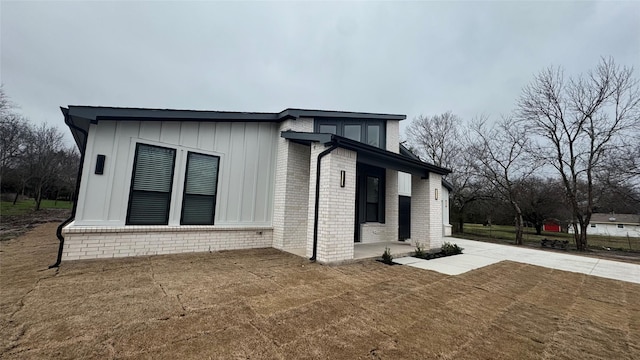 view of side of home featuring brick siding, board and batten siding, and a yard