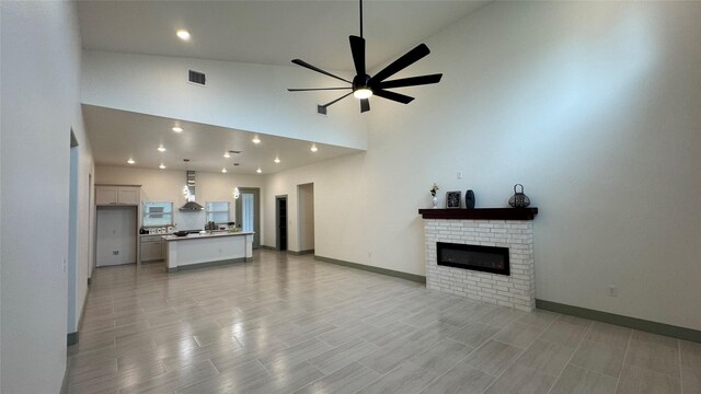 living room with visible vents, baseboards, a brick fireplace, and ceiling fan