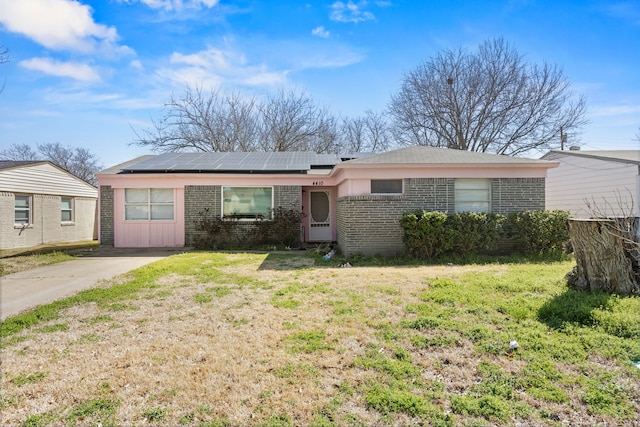 view of front of home featuring a front yard, brick siding, and roof mounted solar panels