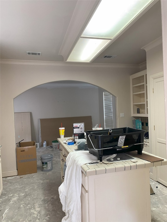 interior space with arched walkways, visible vents, crown molding, and unfinished concrete flooring