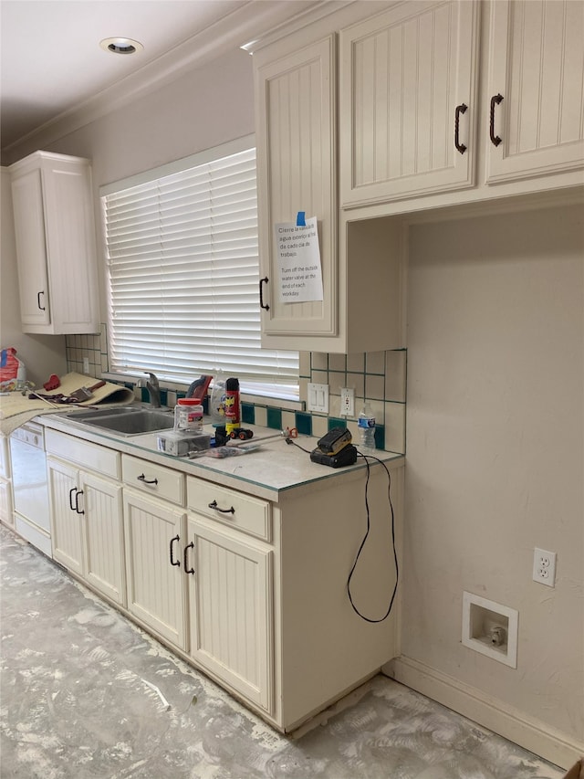 kitchen with tasteful backsplash, baseboards, light countertops, white dishwasher, and a sink