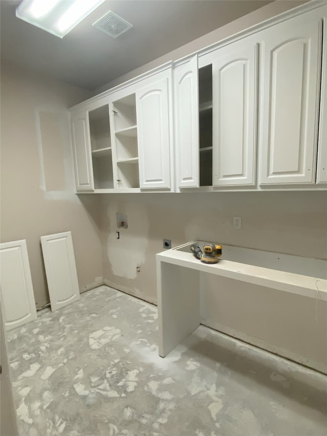 laundry room featuring electric dryer hookup, visible vents, and cabinet space