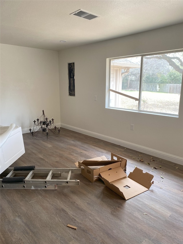 interior space featuring a textured ceiling, wood finished floors, visible vents, and baseboards