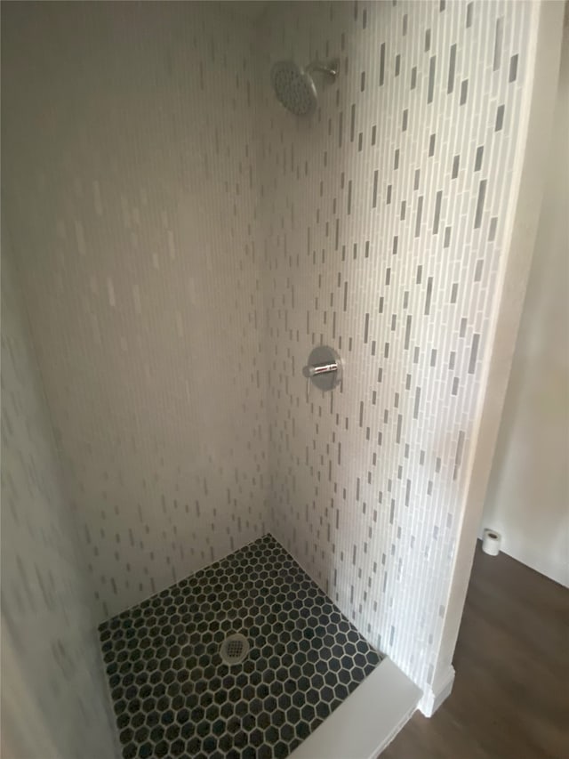 full bath with tiled shower and wood finished floors