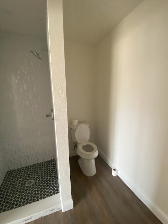 bathroom featuring baseboards, toilet, wood finished floors, and a shower stall