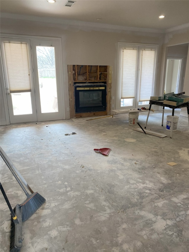 unfurnished living room featuring a glass covered fireplace, visible vents, concrete floors, and ornamental molding