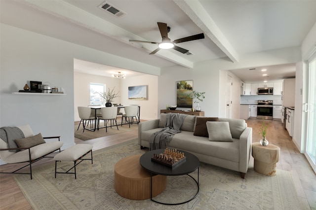 living room with visible vents, beamed ceiling, a ceiling fan, and light wood-style floors