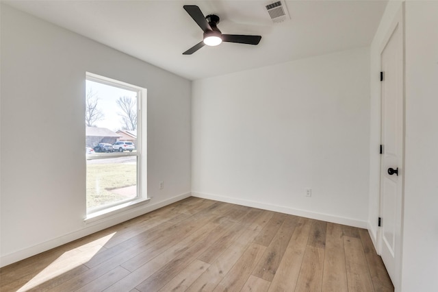 unfurnished room with a ceiling fan, visible vents, light wood-style floors, and baseboards