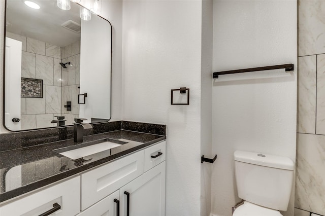 bathroom featuring visible vents, tiled shower, toilet, and vanity