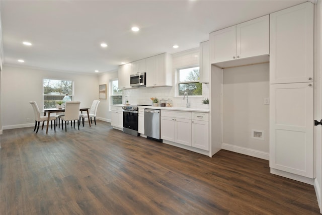 kitchen with decorative backsplash, dark wood-style floors, white cabinets, stainless steel appliances, and a sink