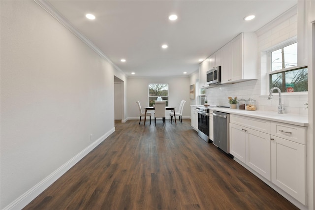 kitchen with dark wood-style floors, baseboards, a sink, appliances with stainless steel finishes, and tasteful backsplash