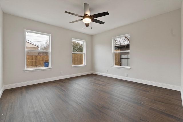 empty room featuring baseboards, ceiling fan, and dark wood-style flooring